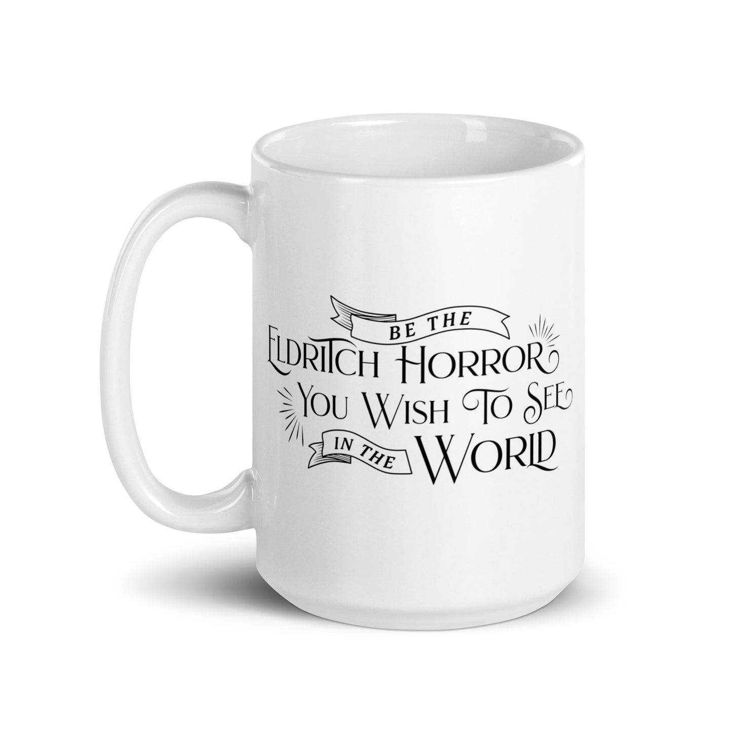 A white, ceramic, 15 ounce mug featuring black text in a semi-gothic style font that reads "Be the Eldritch Horror You Wish To See In The World"