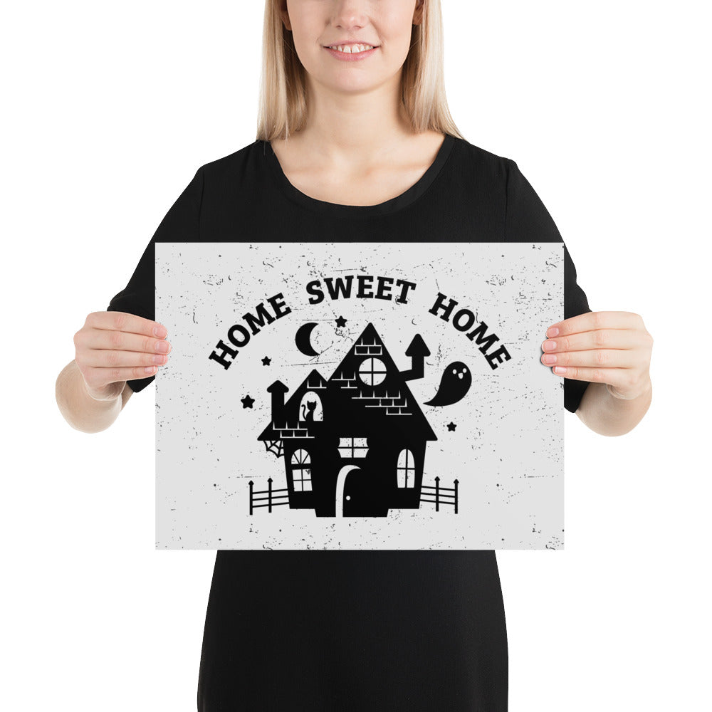 A print of the silhouette of a haunted house. A ghost is flying nearby and a cat is visible in a window. Text above the house reads "HOME SWEET HOME".