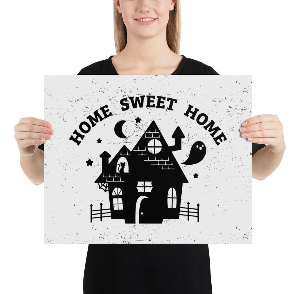 A print of the silhouette of a haunted house. A ghost is flying nearby and a cat is visible in a window. Text above the house reads "HOME SWEET HOME".