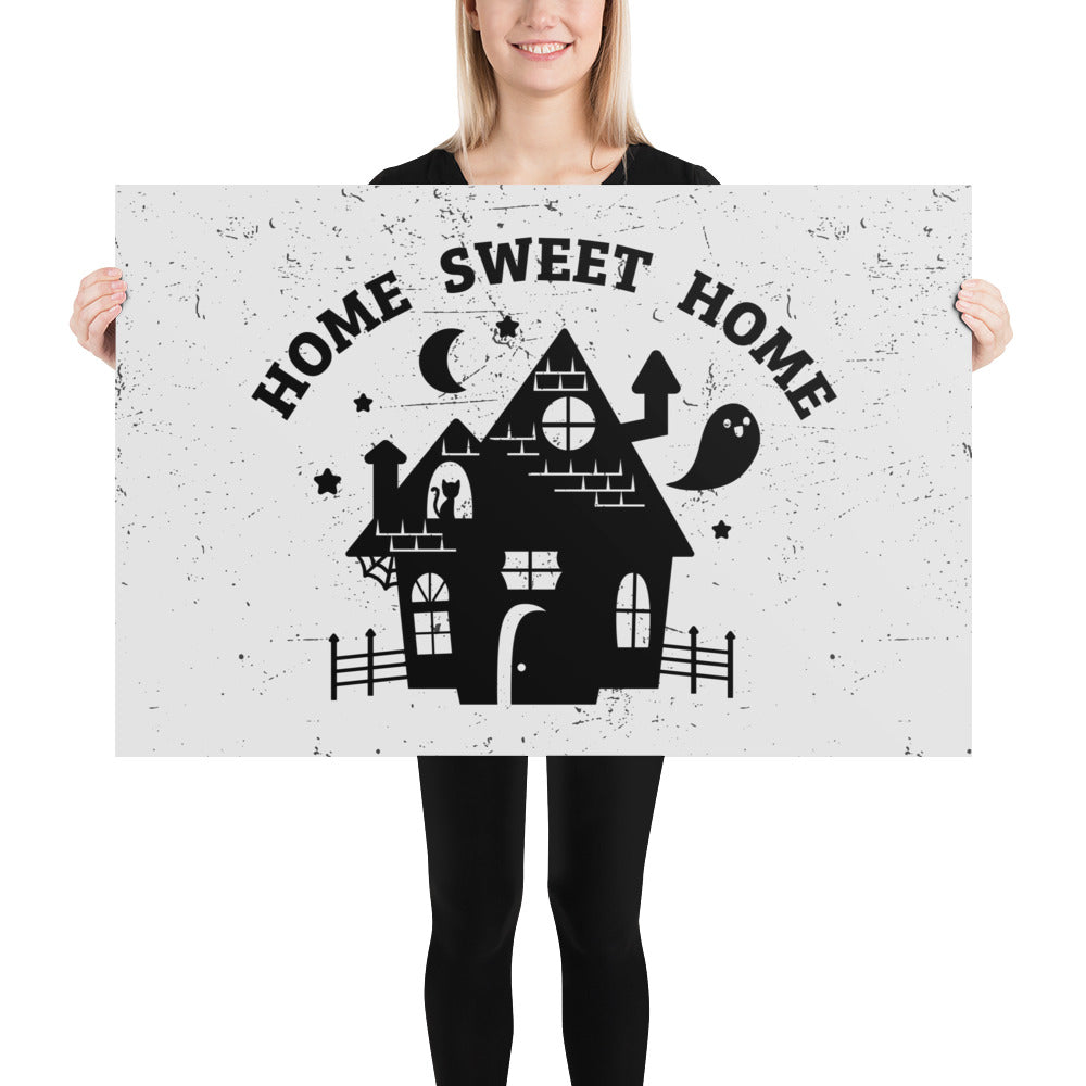 A print of the silhouette of a haunted house. A ghost is flying nearby and a cat is visible in a window. Text above the house reads "HOME SWEET HOME".