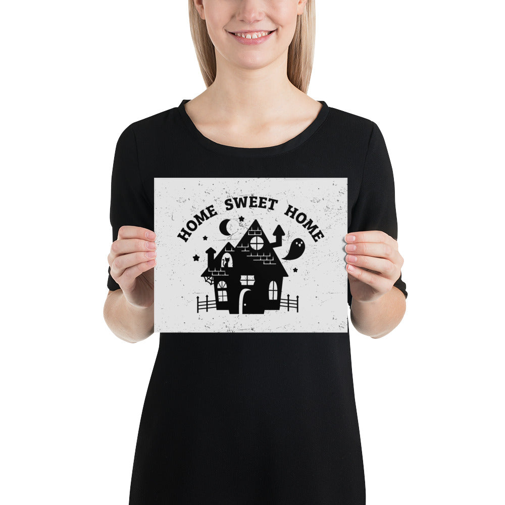 A print of the silhouette of a haunted house. A ghost is flying nearby and a cat is visible in a window. Text above the house reads "HOME SWEET HOME".