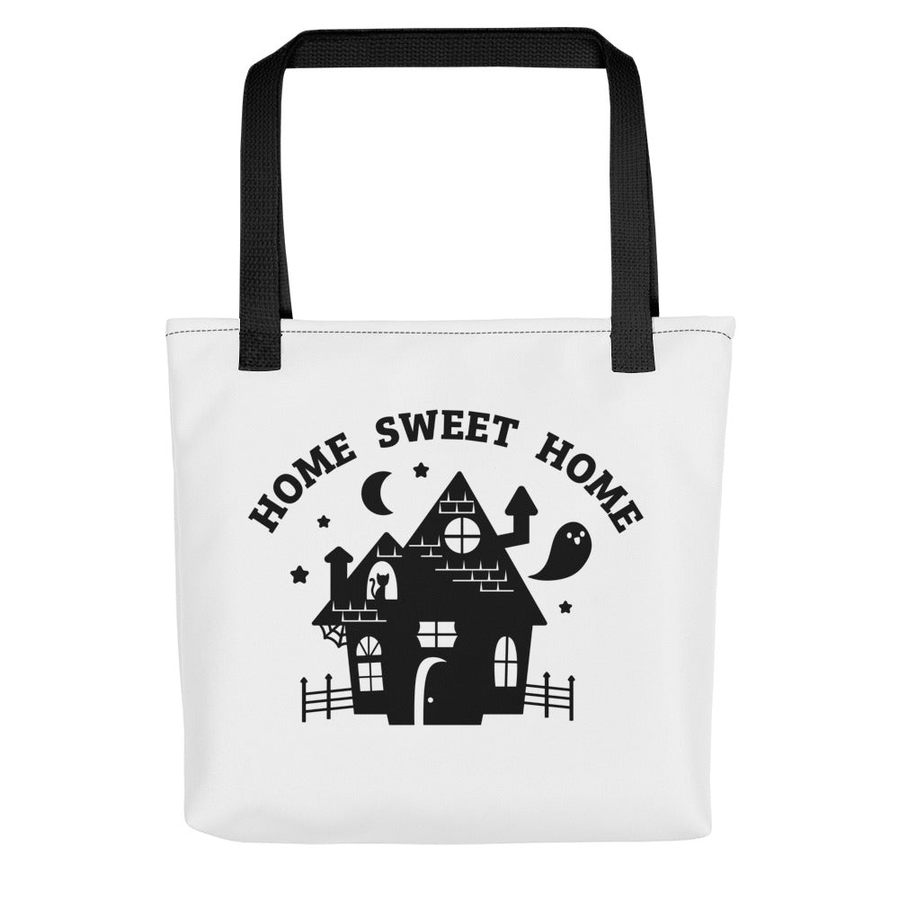 A white tote bag with black stitching and handles. Featured on the bag is a black silhouette of a haunted house. Text above the house reads "Home Sweet Home"