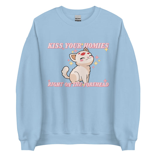 A light blue crewneck sweatshirt featuring an illustration of a soft white kitten. Lipstick kiss marks are on the kitten's forehead, and its face is surrounded by sparkles. Pink text around the kitten reads "Kiss your homies right on the forehead."