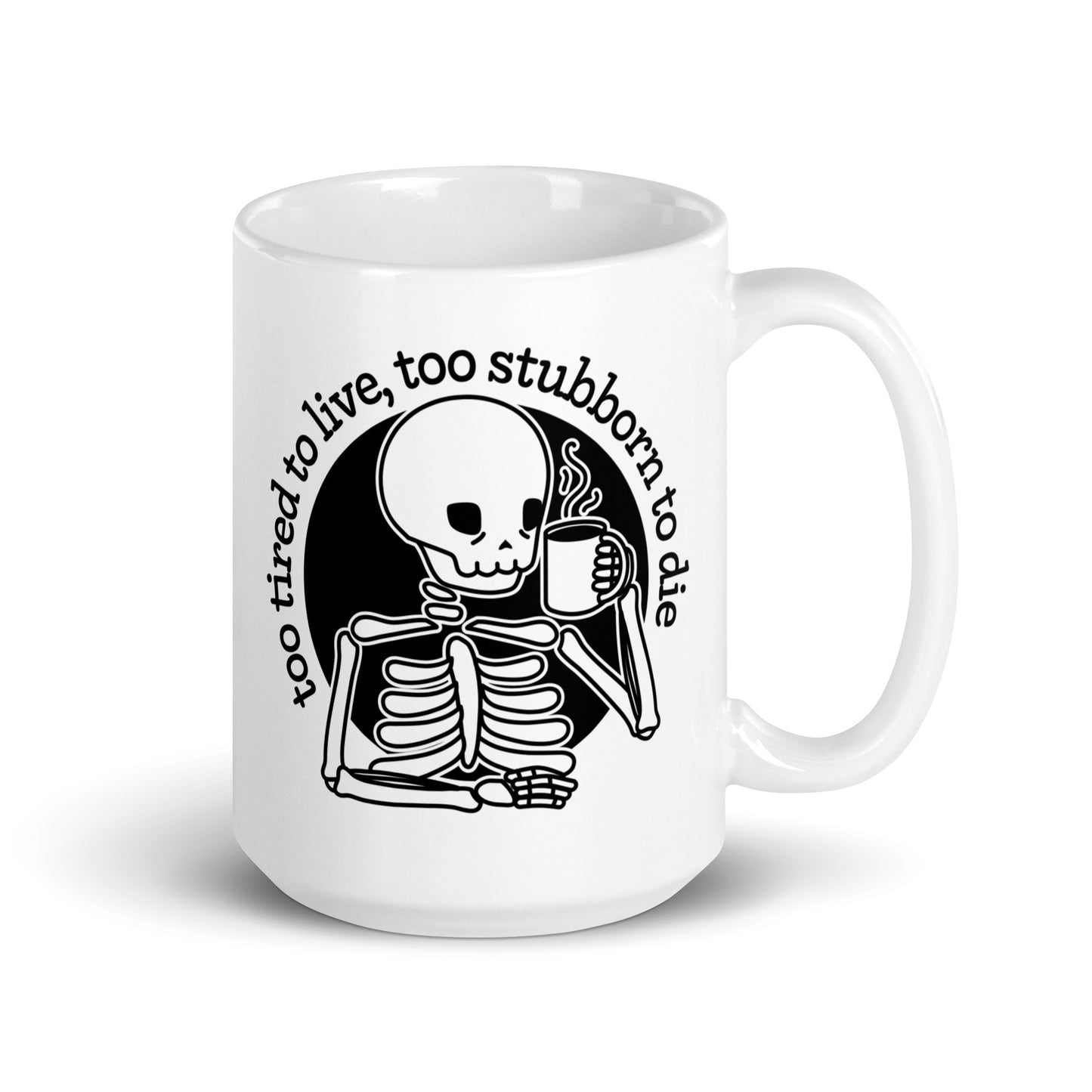 A white 15 ounce ceramic mug featuring a tired-looking skeleton holding a steaming mug. Text above the skeleton reads "too tired to live, too stubborn to die".