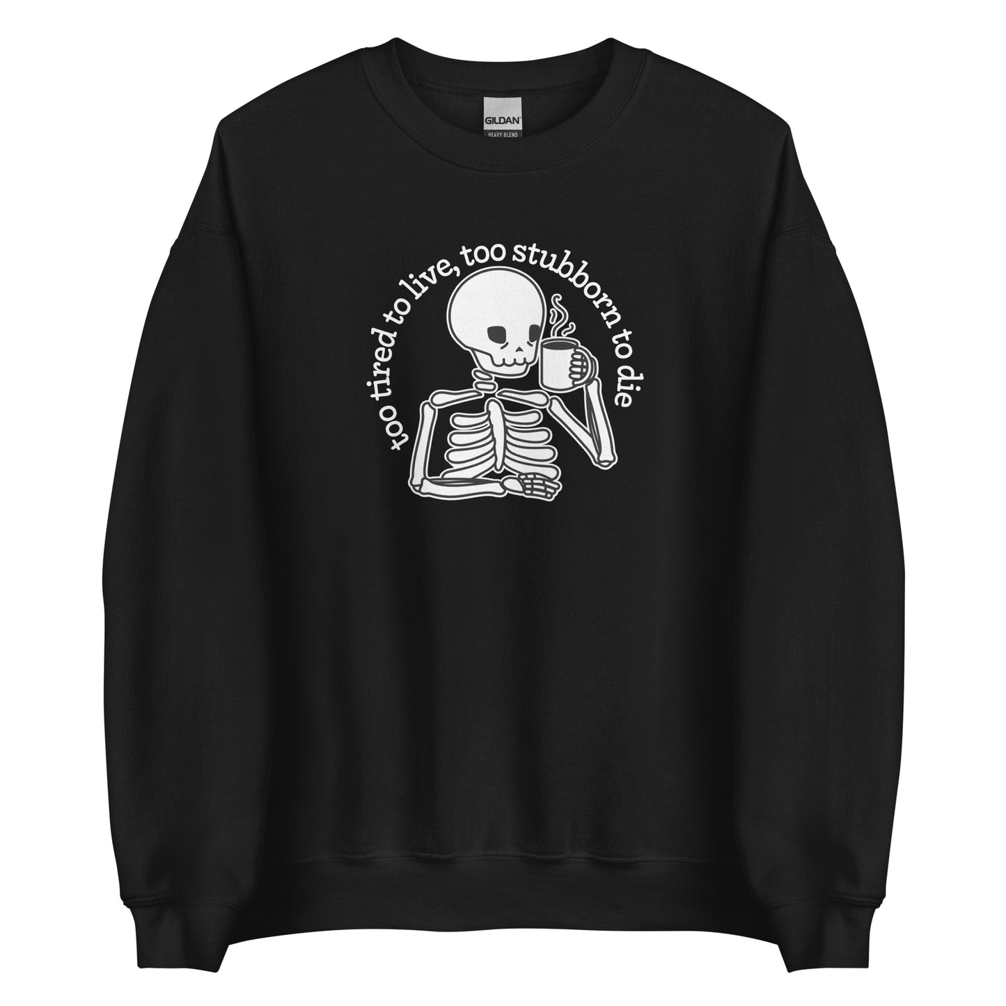A black crewneck sweatshirt featuring an illustration of a tired-looking skeleton holding a steaming mug. Text in an arc above the skeleton reads "too tired to live, too stubborn to die"