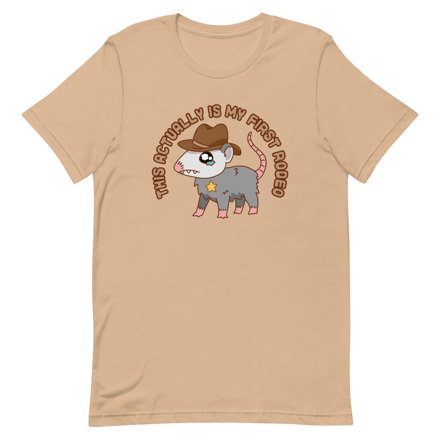 A tan crewneck t-shirt featuring an illustration of a cute and nervous possum wearing a cowboy hat and sherrif's star badge. Text above the possum in an arc reads "this actually is my first rodeo".