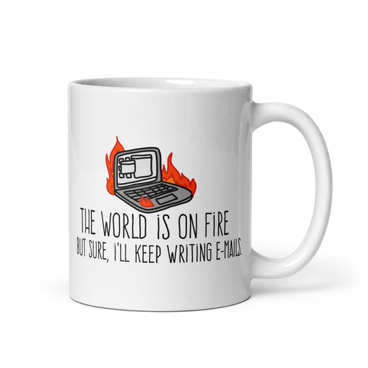 A white ceramic mug featuring a wobbly illustration of a laptop on fire. Text underneath the laptop reads "The world is on fire but sure, I'll keep writing e-mails"