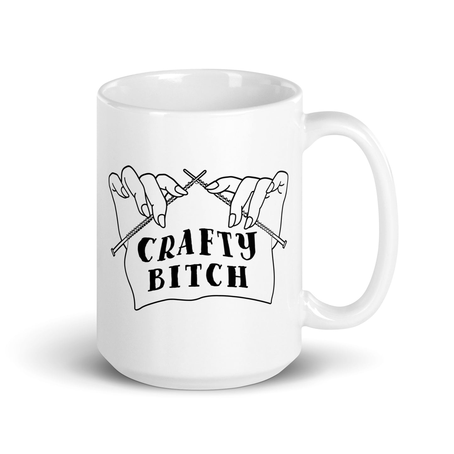 A white ceramic 15 ounce coffee mug featuring a single-color illustration of a pair of hands holding knitting needles. Fabric on the needles features text that reads "crafty bitch".