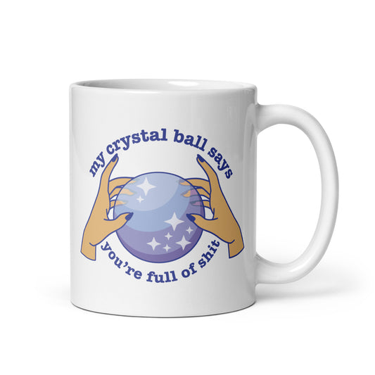 A white 11 ounce ceramic mug with a picture of hands on a crystal ball and text reading "My crystal ball says you're full of shit"