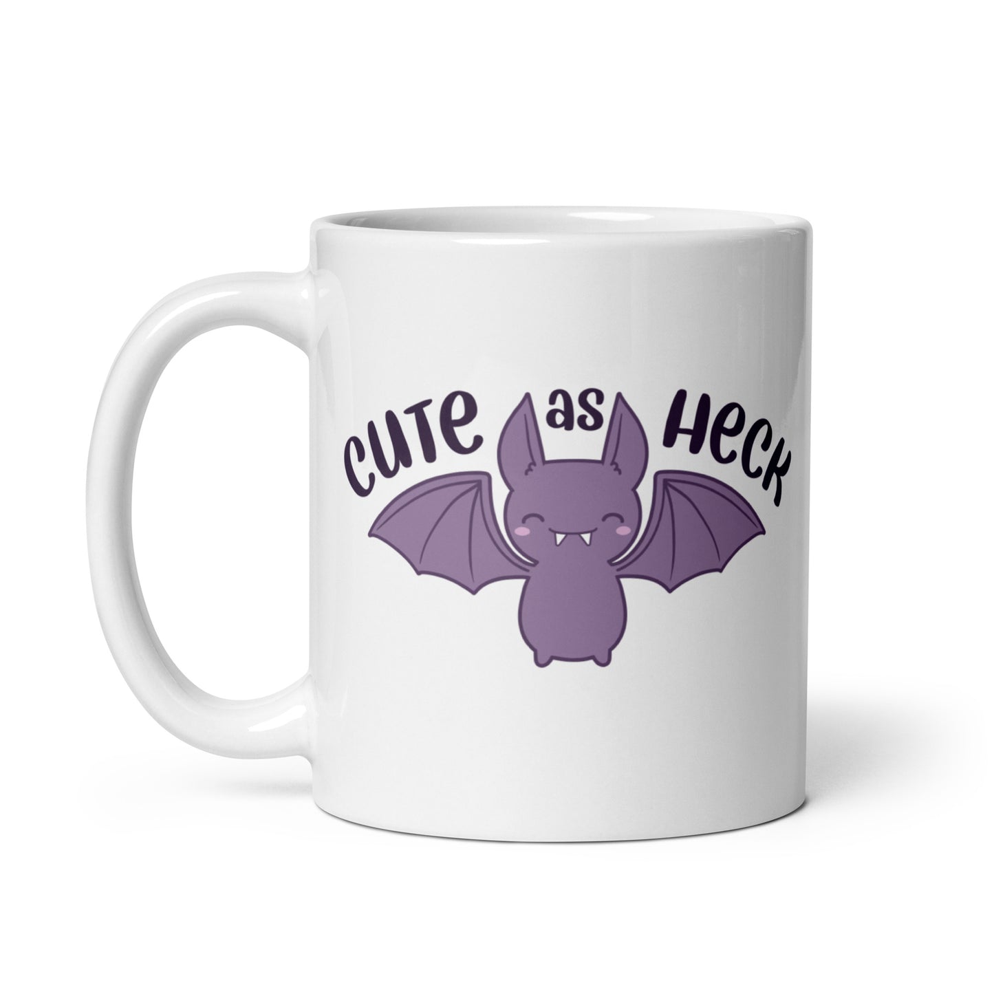 An 11 ounce white ceramic mug featuring an illustration of a smiling purple bat. Above the bat is text that reads "Cute As Heck"