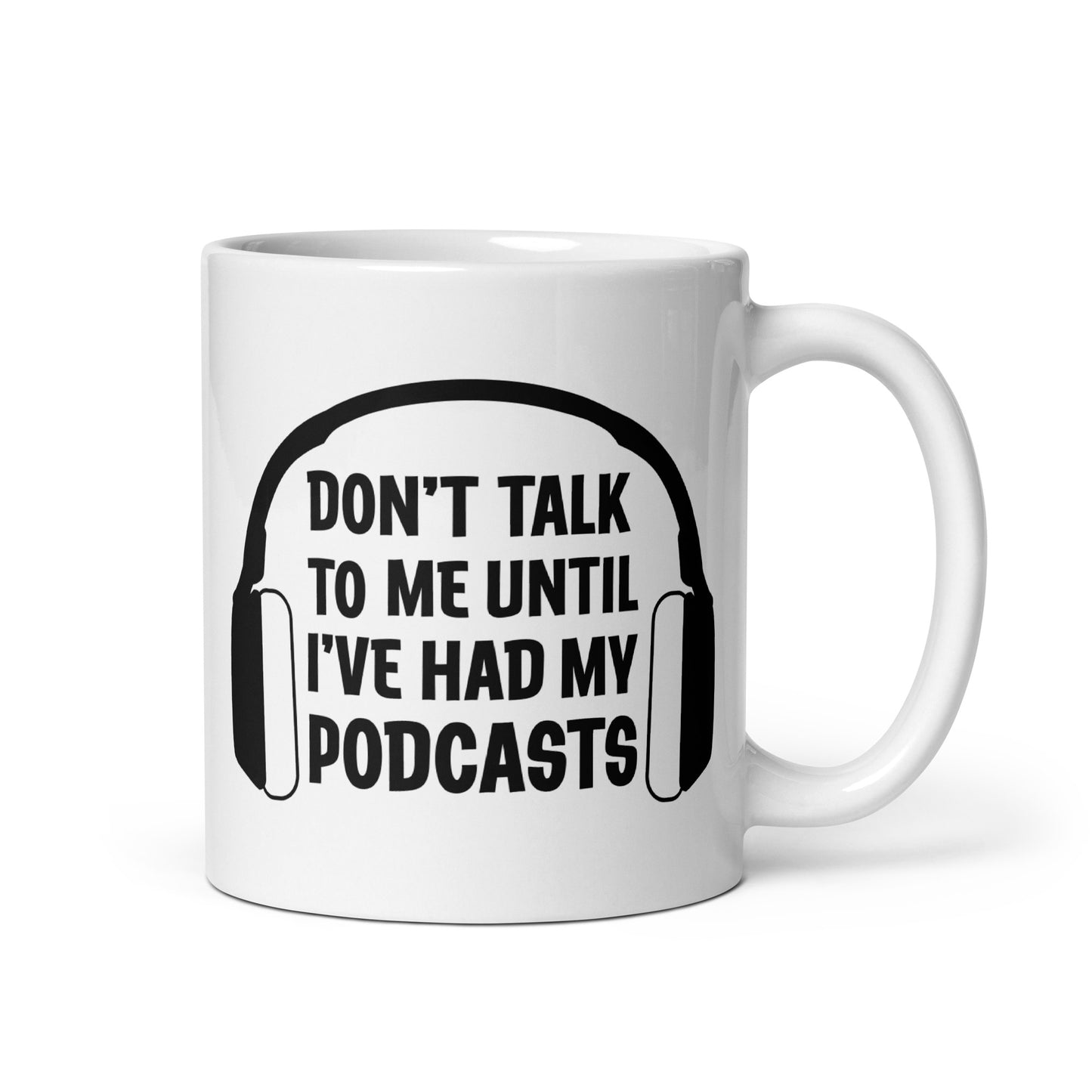 A white 11 ounce ceramic coffee mug featuring an image of headphones surrounding text reading "Don't talk to me until I've had my podcasts"