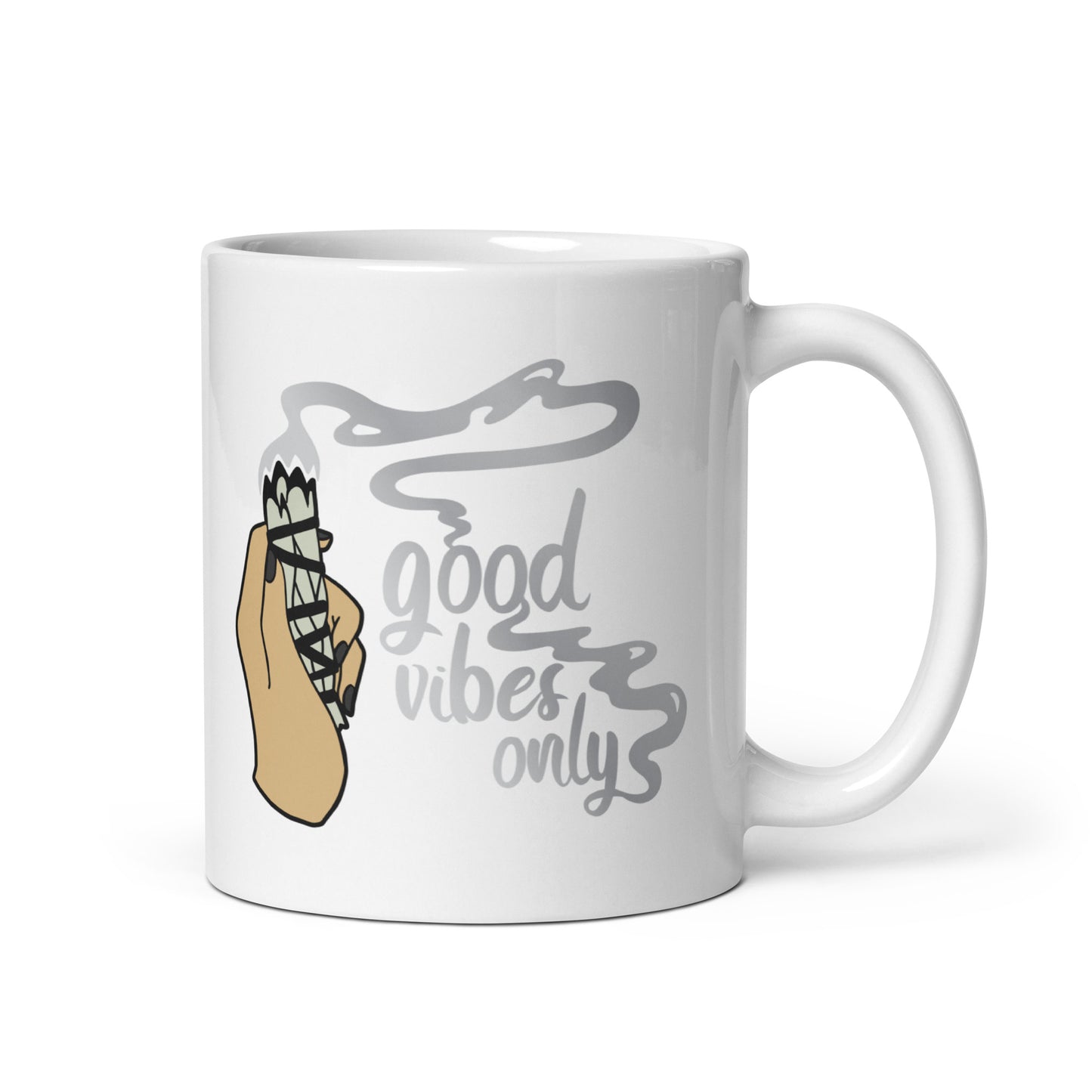 An 11 ounce white ceramic coffee mug featuring an illustration of a hand holding a sage smudge stick. Smoke flows from the tip of the sage and forms words that read "good vibes only"