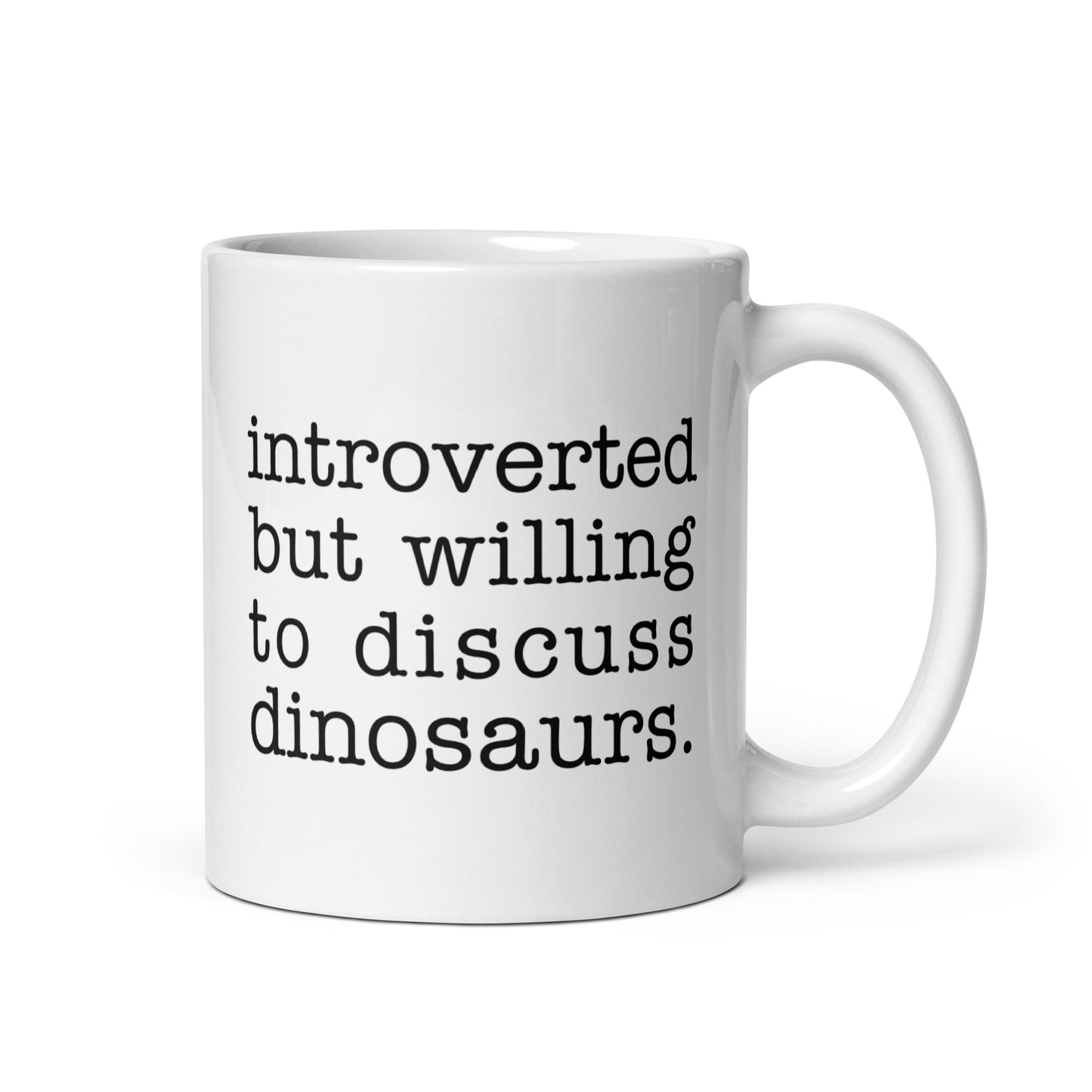 A white 11 ounce ceramic mug with text reading "introverted but willing to discuss dinosaurs"