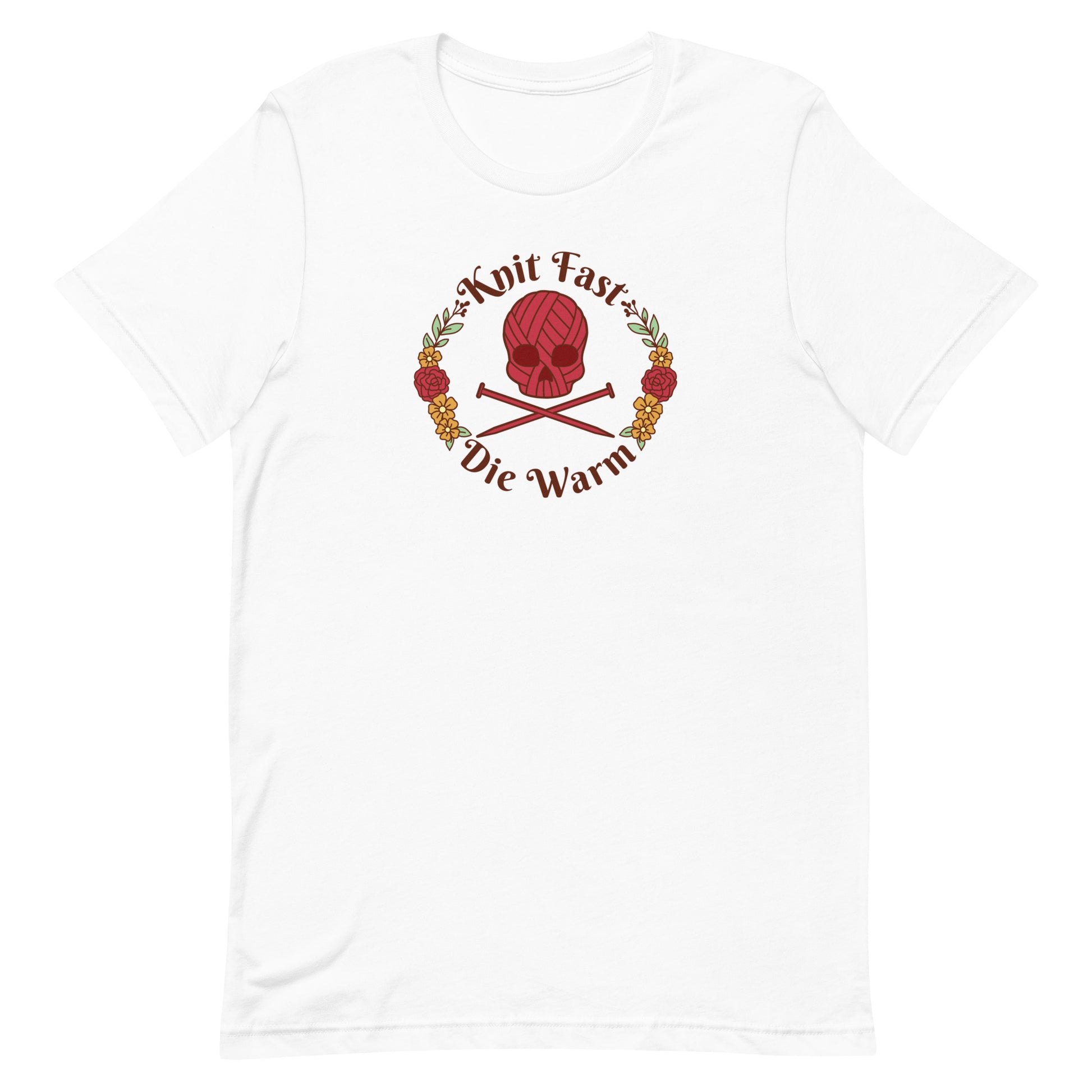 A white crewneck t-shirt featuring an image of a skull and crossbones made of yarn and knitting needles. A floral wreath surrounds the skull, along with words that read "Knit Fast, Die Warm"