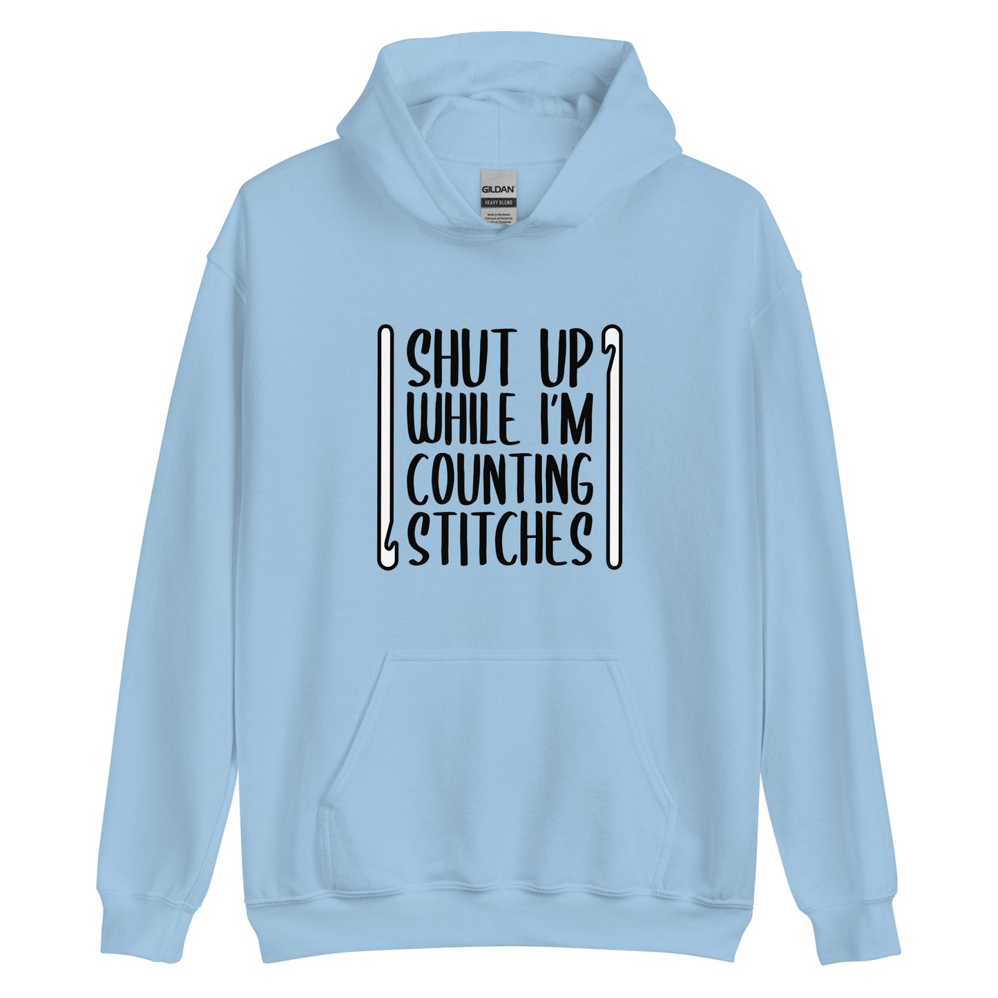 A light blue hooded sweatshirt featuring black text that reads "Shut up while I'm counting stitches." The text is framed by a crochet hook to the left and right.