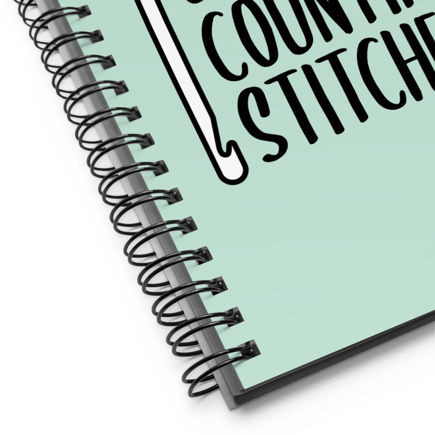 A close-up image of a mint green wire-bound notebook. The image focuses on the wire "o" binding.