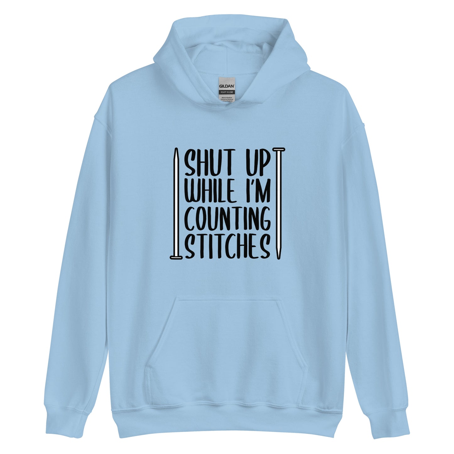 A light blue hooded sweatshirt with black text surrounded by two knitting needles. The text reads "Shut up while I'm counting stiches".
