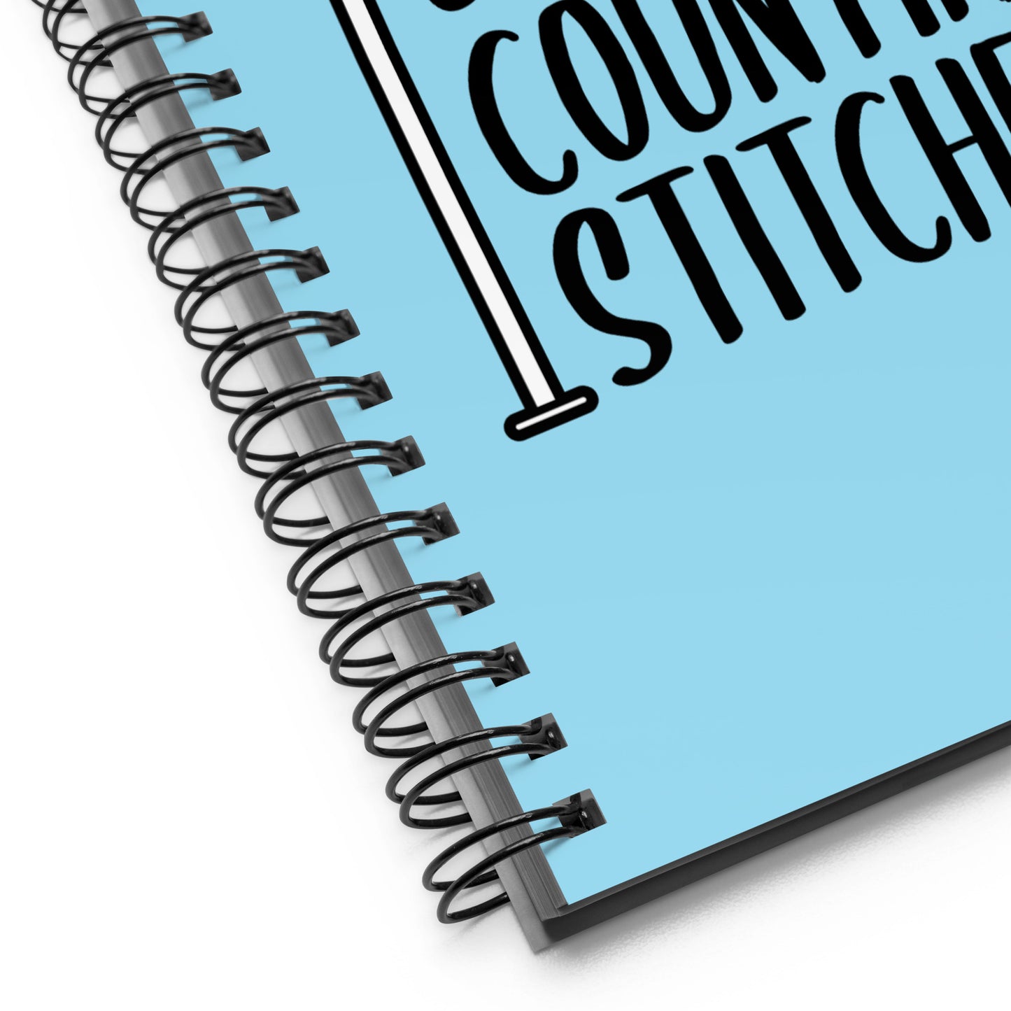 A close-up image of a blue wire-bound notebook. The image focuses on the wire "o" binding.