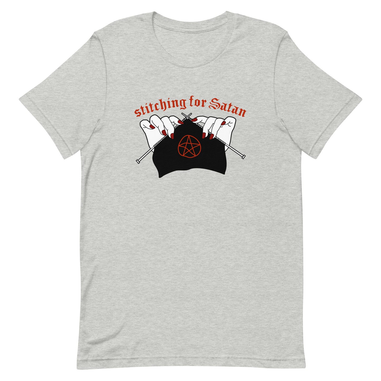 A grey crewneck t-shirt featuring an illustration of pale white hands with red fingernails holding knitting needles. Fabric on the needles features a red pentagram. Text above the hands reads "stitching for Satan" in a gothc red font.