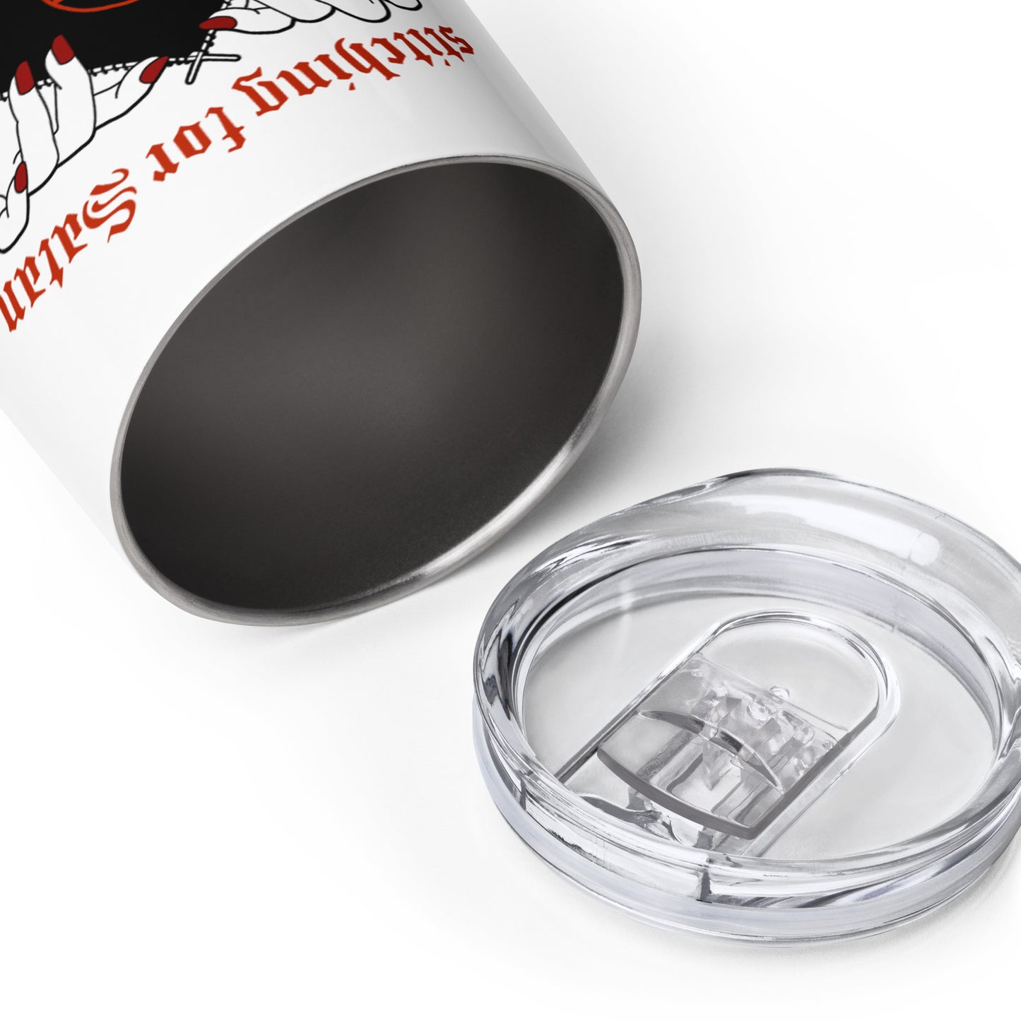 A white 12 ounce wine tumbler laying on its side with the opening facing the camera. The clear plastic lid of the tumbler is placed nearby.