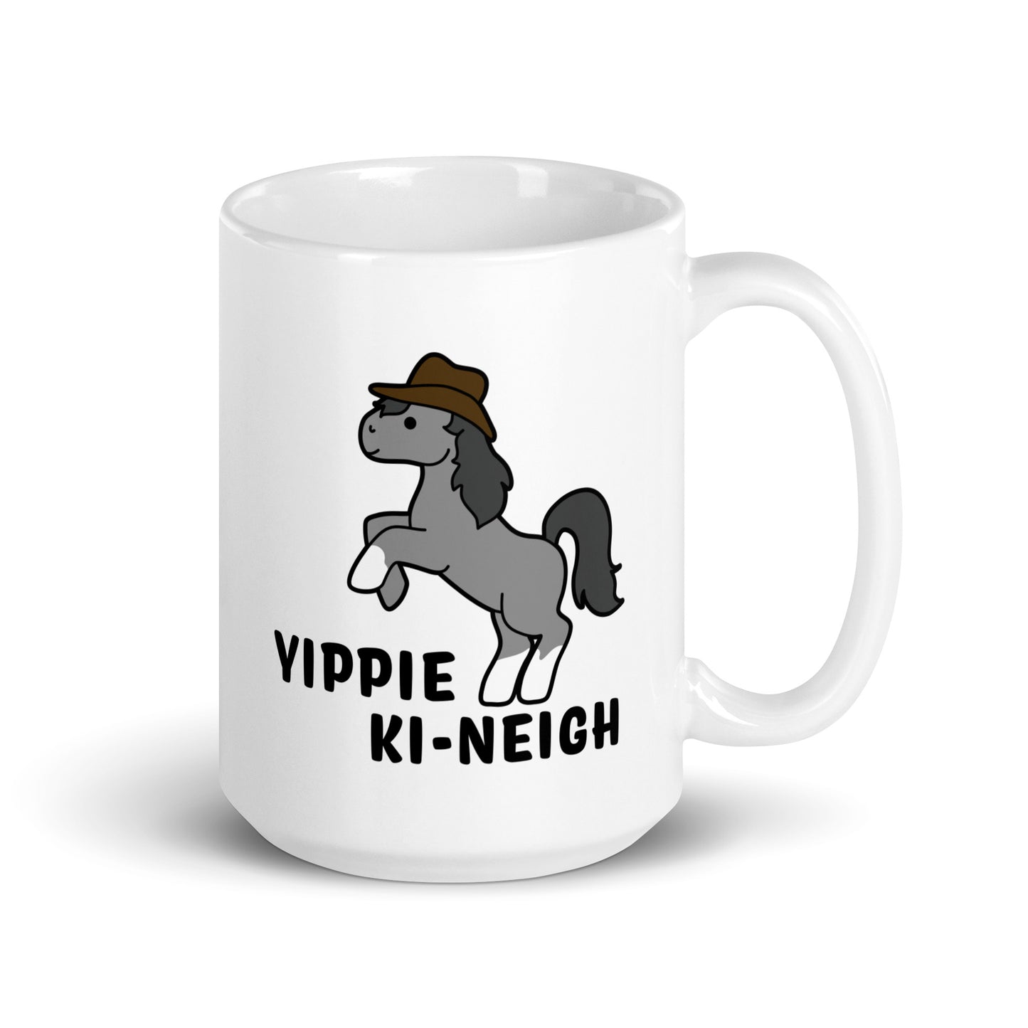 A white 15 ounce ceramic coffee mug featuring an illustration of a smiling grey pony rearing and wearing a cowboy hat. Text underneath the pony reads "Yippie Ki-Neigh"