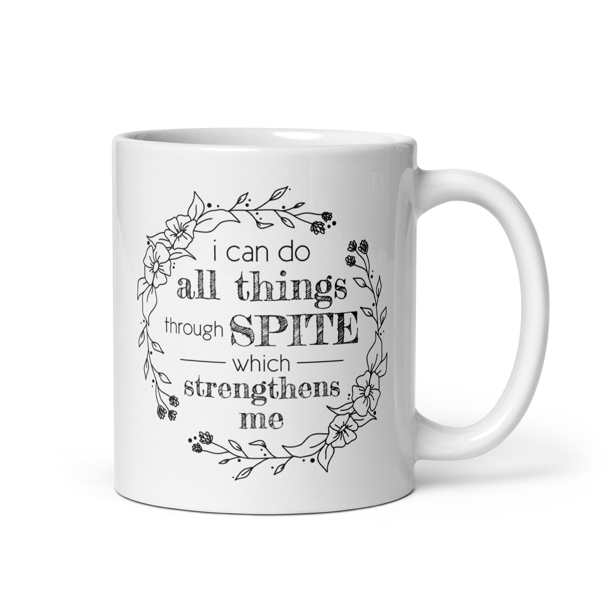 A white ceramic mug featuring a simple illustration of a floral wreath. Inside the wreath is text that reads "I can do all things through SPITE which motivates me"