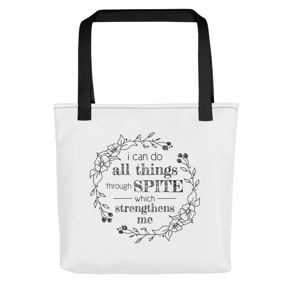 A white tote bag with black handles, featuring a simple illustration of a floral wreath. Inside the wreath is text that reads "I can do all things through SPITE which motivates me"