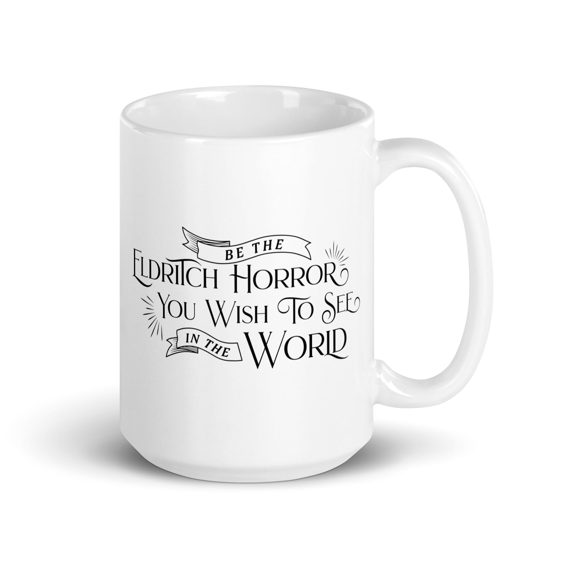 A white, ceramic, 15 ounce mug featuring black text in a semi-gothic style font that reads "Be the Eldritch Horror You Wish To See In The World"