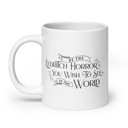 A white, ceramic, 20 ounce mug featuring black text in a semi-gothic style font that reads "Be the Eldritch Horror You Wish To See In The World"