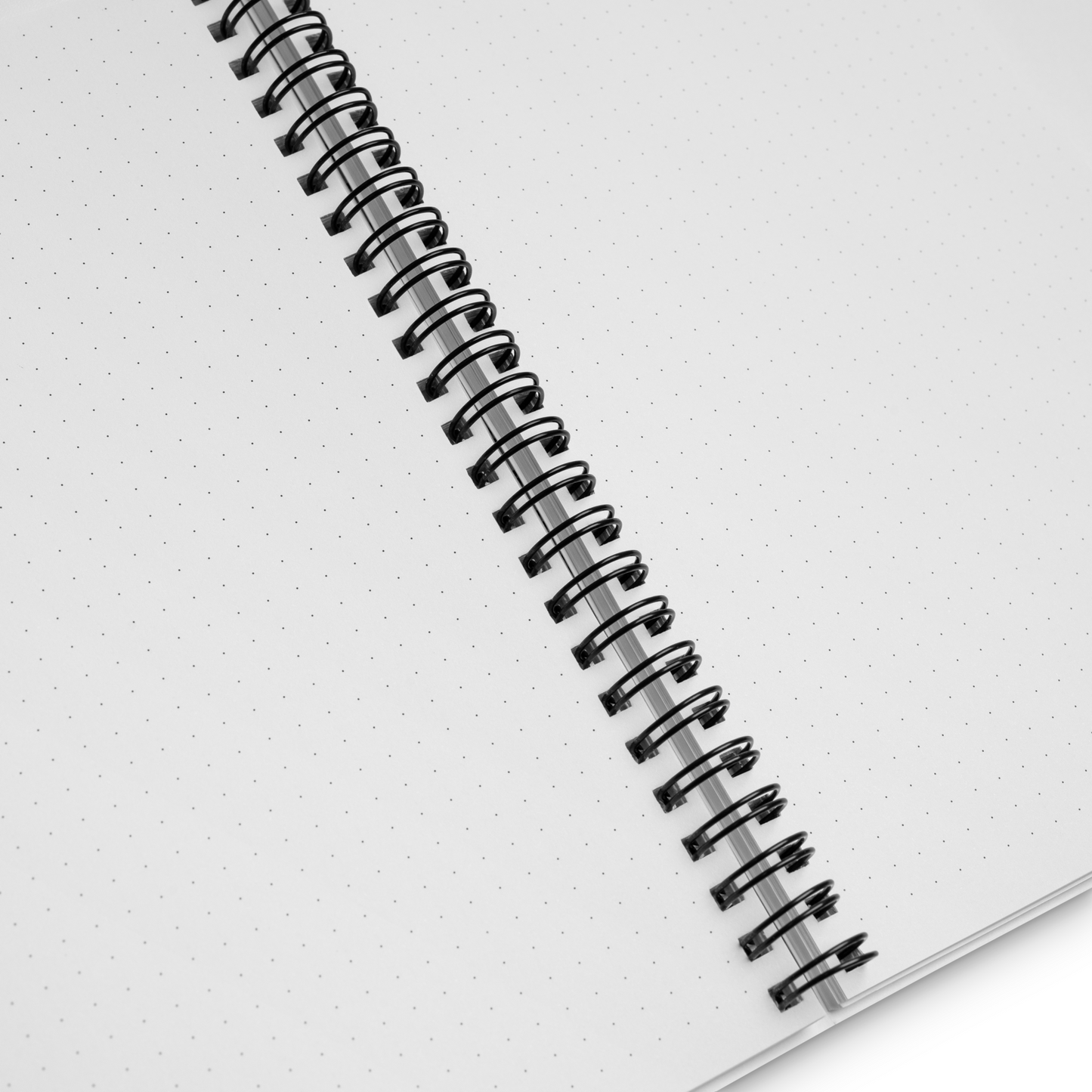 A close-up image of a wire-bound notebook with dot-grid pages. The o-rings binding the notebook are black.
