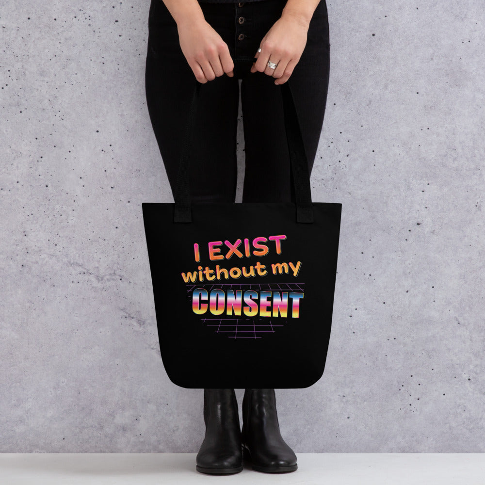 A waist-down image of a model wearing all black, holding a black tote bag featuring a brightly colored 80's style graphic with colorful text that reads "I exist without my consent"