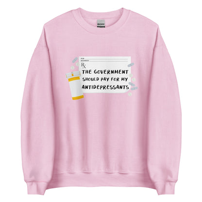 A pink crewneck sweatshirt featuring an image of a subscription page with text that reads "The government should pay for my antidepressants". Pills and an empty orange pill bottle surround the RX sheet.