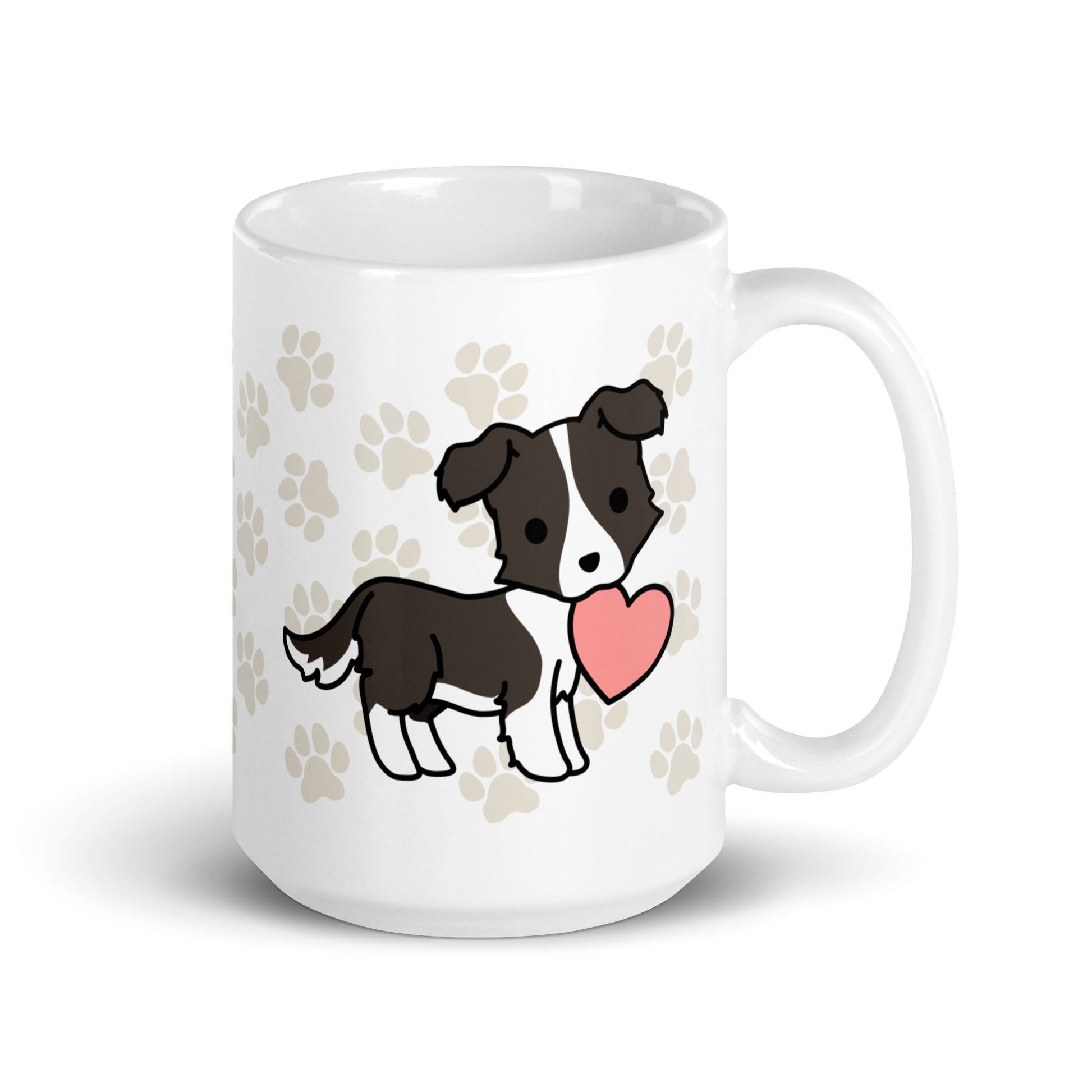 A white 15 ounce ceramic mug with a pattern of light brown pawprints all over. The mug also features a stylized illustration of a Border Collie holding a heart in its mouth.
