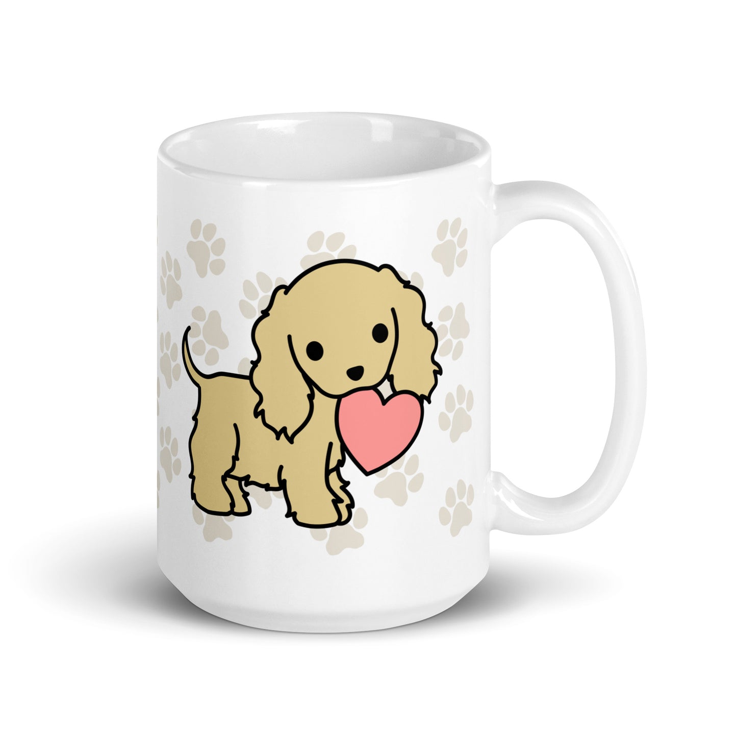 A white 15 ounce ceramic mug with a pattern of light brown pawprints all over. The mug also features a stylized illustration of a Cocker Spaniel holding a heart in its mouth.