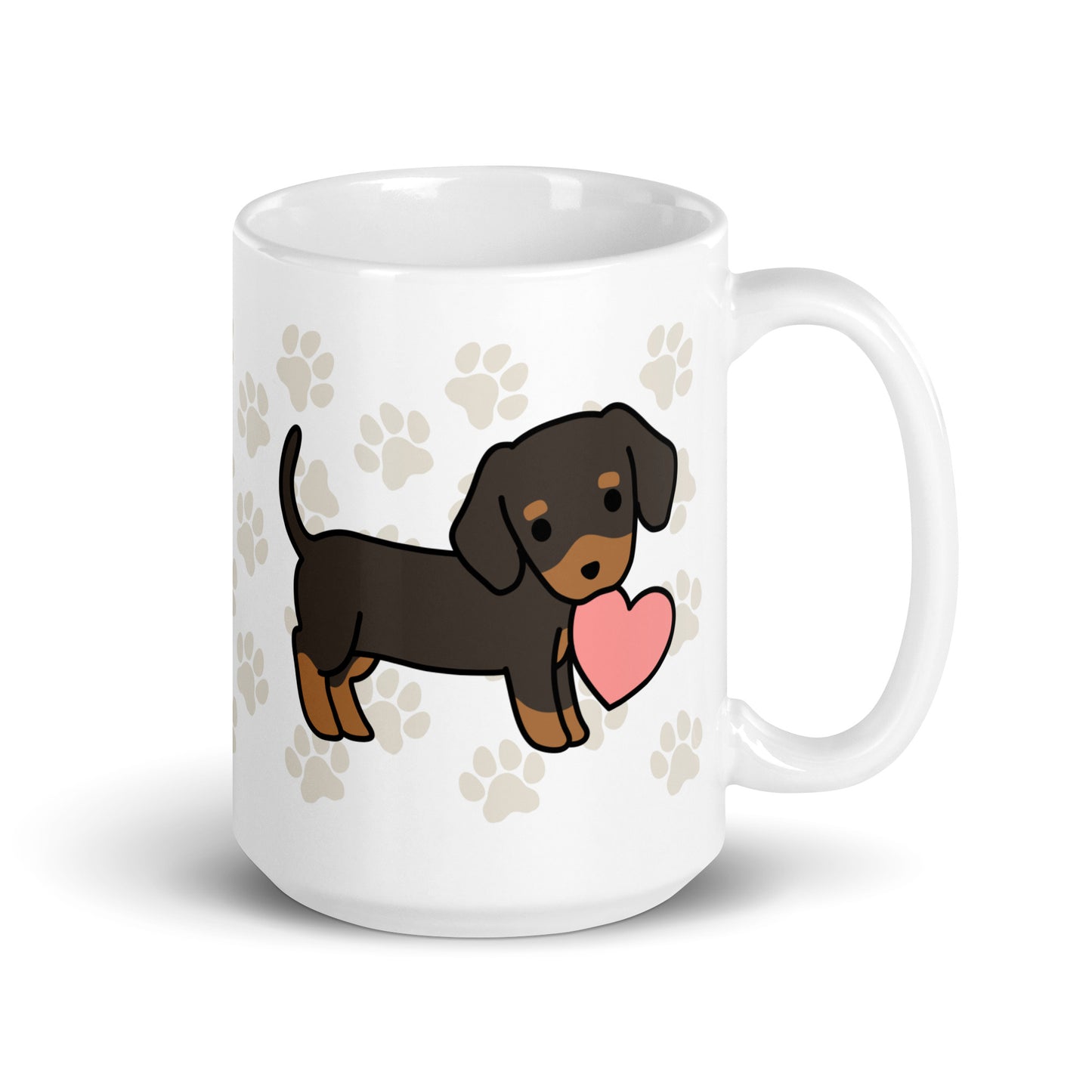 A white 15 ounce ceramic mug with a pattern of light brown pawprints all over. The mug also features a stylized illustration of a Dachshund holding a heart in its mouth.