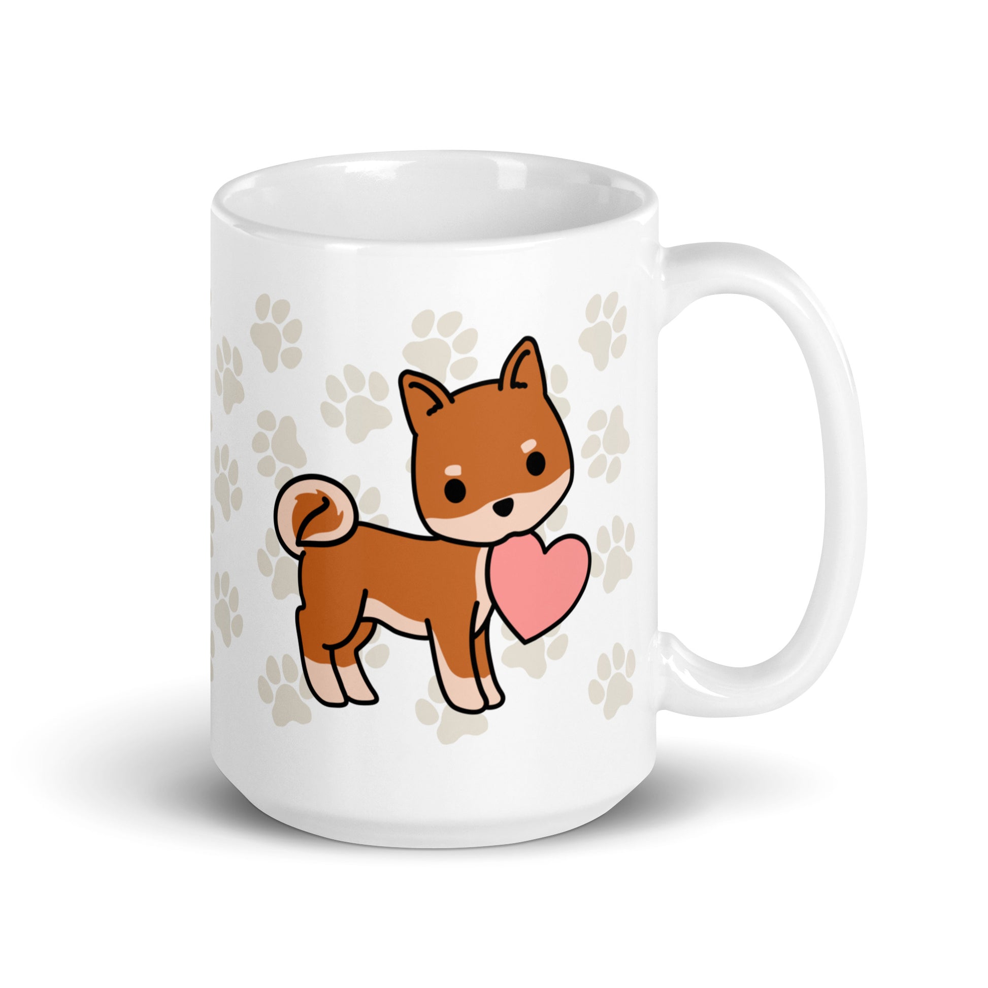 A white 15 ounce ceramic mug with a pattern of light brown pawprints all over. The mug also features a stylized illustration of a Shiba Inu holding a heart in its mouth.