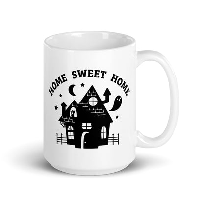 A white 15 ounce ceramic coffee mug featuring an illustration of a haunted house. Text above the house in an arc reads "Home Sweet Home"