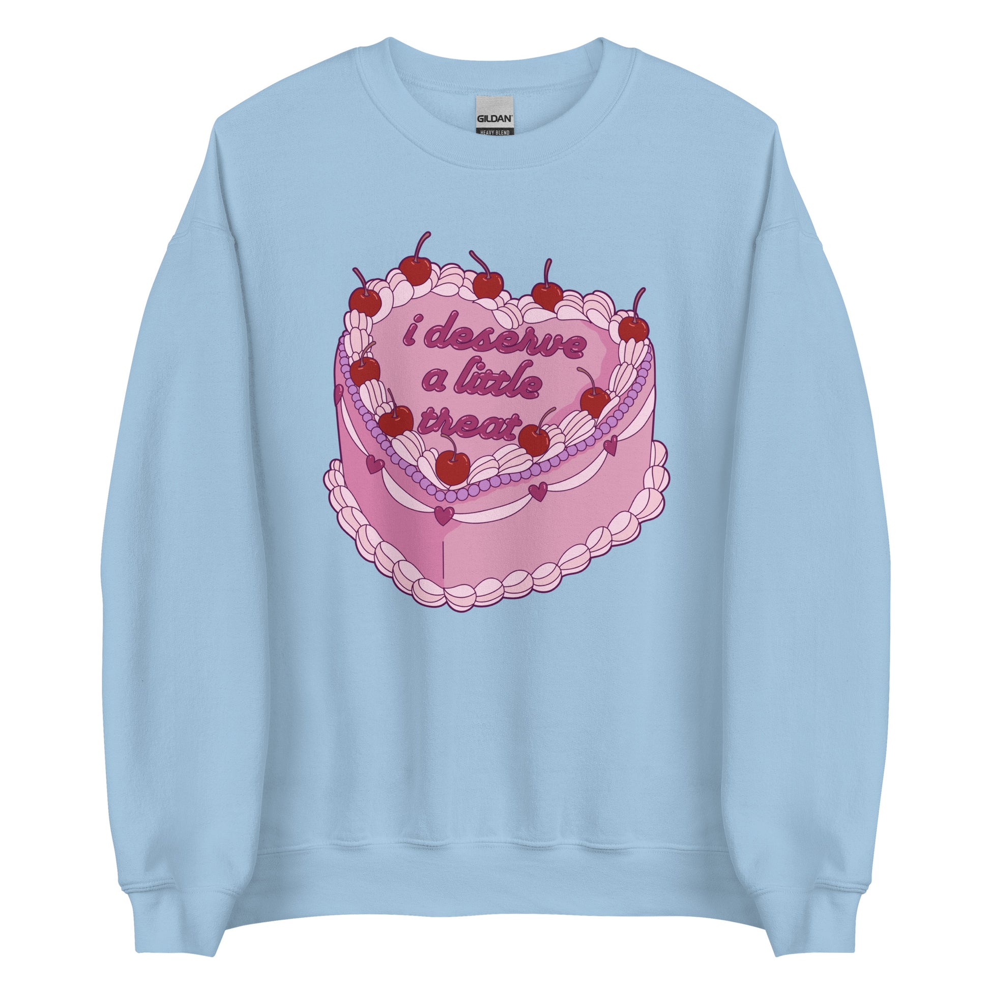 A light blue crewneck sweatshirt featuring an illustration of an elaborately decorated pink cake. Icing on the cake reads "i deserve a little treat" in a cursive font.