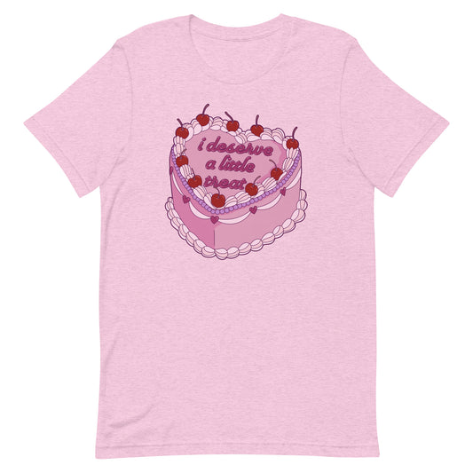 A heathered pink crewneck t-shirt featuring an illustration of an elaborately decorated pink cake. Icing on the cake reads "i deserve a little treat" in a cursive font.