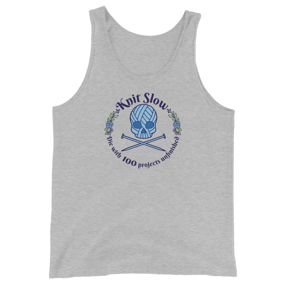 A blue tank top featuring an image of a skull and crossbones made of yarn and knitting needles. A floral wreath surrounds the skull, along with words that read "Knit Slow, Die with 100 projects unfinished"