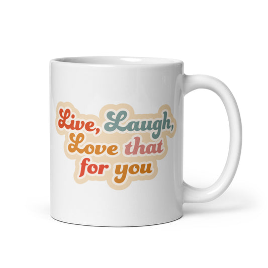 A white 11 ounce cereamic coffee mug featuring colorful, cursive text that reads "Live, Laugh, Love that for you."
