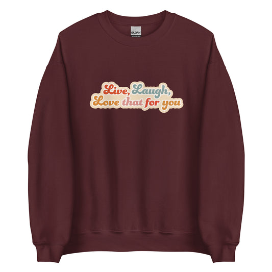 A maroon crewneck sweatshirt featuring colorful, cursive text that reads "Live, Laugh, Love that for you"
