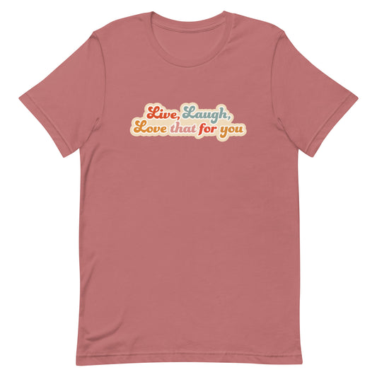 A dusty pink crewneck t-shirt featuring a cursive, colorful font that reads "Live, Laugh, Love that for you".