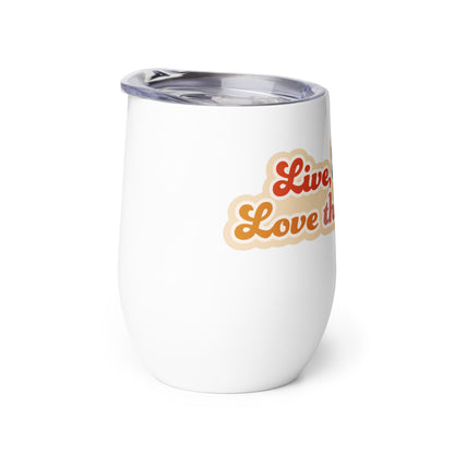 A side view of a white 12 ounce wine tumbler with a plastic lid. The tumbler is decorated with colorful text with a peach-colored outline, which reads "Live, Laugh, Love that for you"