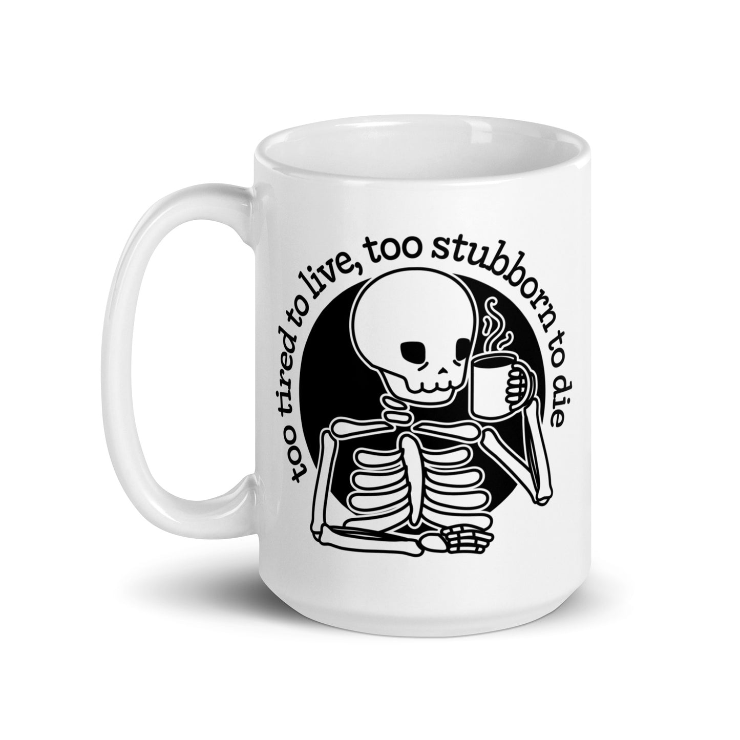 A white 15 ounce ceramic mug featuring a tired-looking skeleton holding a steaming mug. Text above the skeleton reads "too tired to live, too stubborn to die".