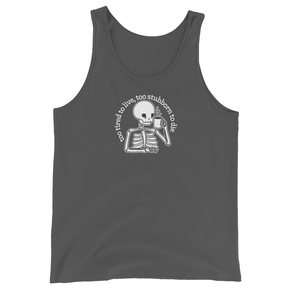 A dark grey tank top featuring a tired-looking skeleton holding a steaming mug. Text above the skeleton in an arc reads "too tired to live, too stubborn to die"