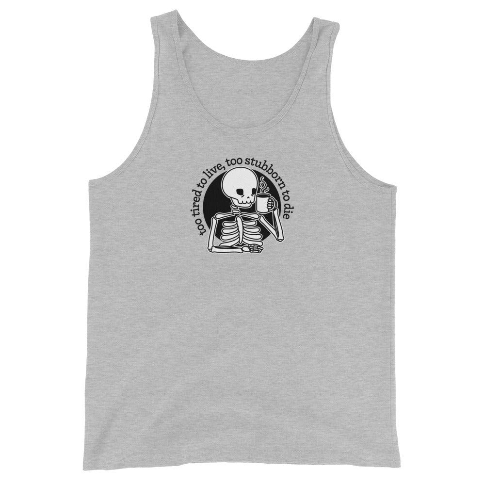 A light heathered grey tank top featuring a tired-looking skeleton holding a steaming mug. Text above the skeleton in an arc reads "too tired to live, too stubborn to die"