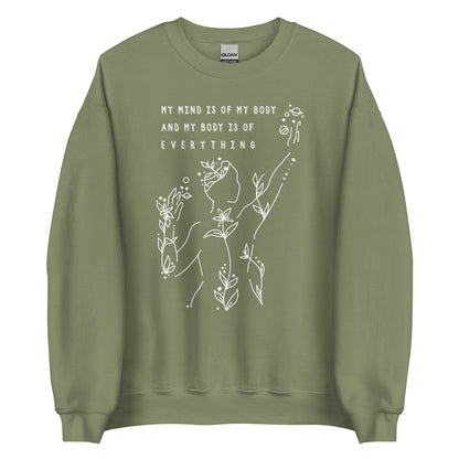 An olive green crewneck sweatshirt featuring an abstract illustration of a figure whose body is spreading out into plants and planets and stars. Text above the figure reads "My mind is of my body and my body is of everything."