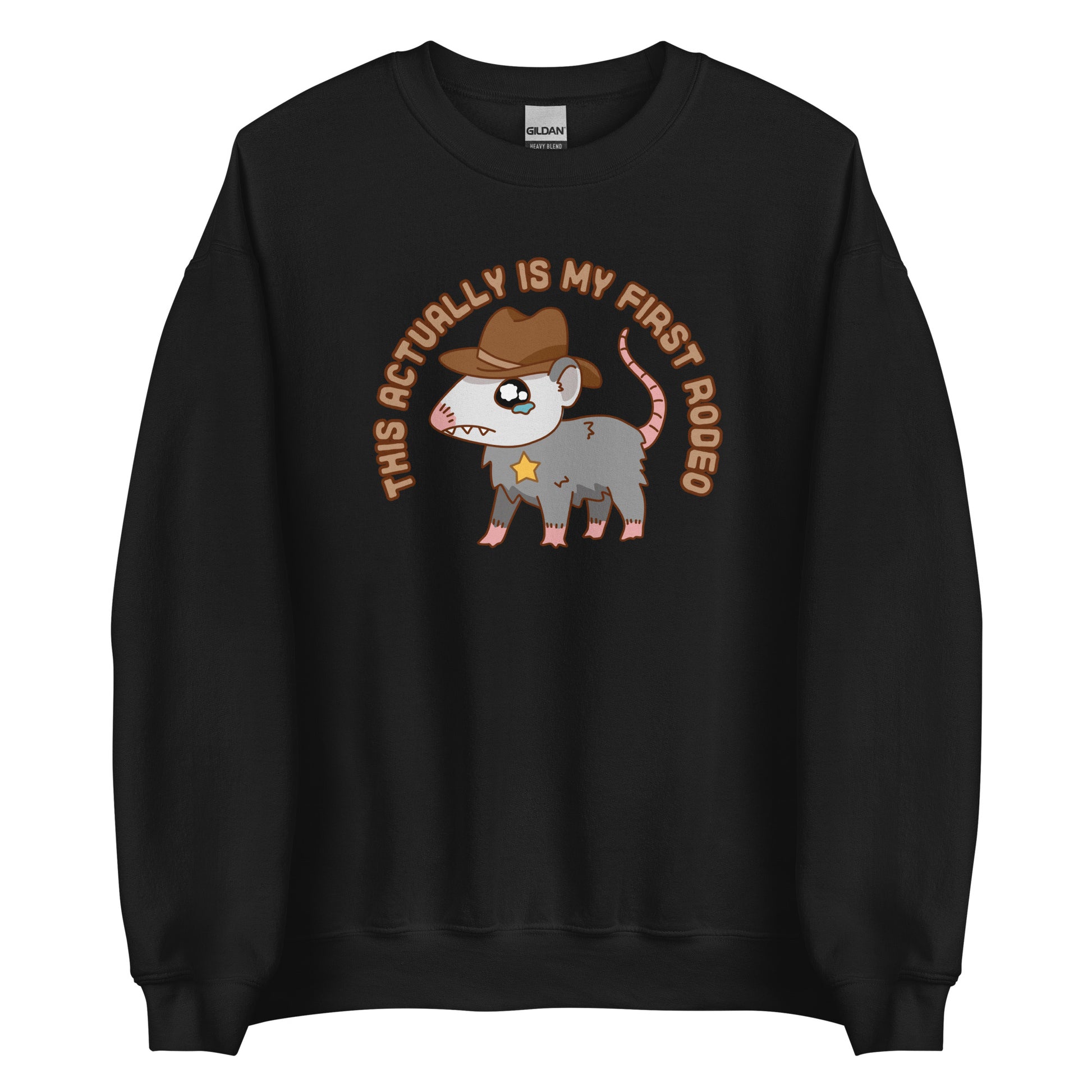 A black crewneck sweatshirt featuring an illustration of a cute and nervous possum wearing a cowboy hat and sherrif's star badge. Text above the possum in an arc reads "this actually is my first rodeo".