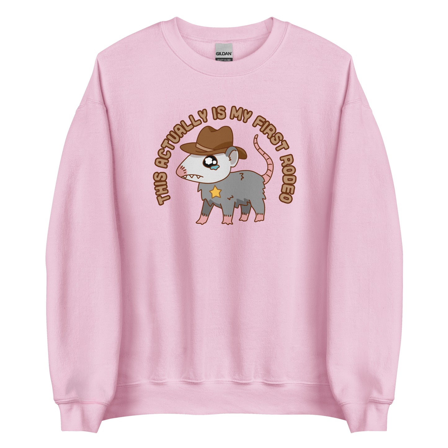 A pink crewneck sweatshirt featuring an illustration of a cute and nervous possum wearing a cowboy hat and sherrif's star badge. Text above the possum in an arc reads "this actually is my first rodeo".